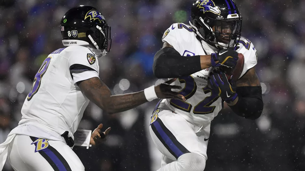 Baltimore Ravens quarterback Lamar Jackson (8) hands off the ball to running back Derrick Henry (22) during the first quarter of an NFL divisional playoff football game against the Buffalo Bills, Sunday, Jan. 19, 2025, in Orchard Park, N.Y. (AP Photo/Adrian Kraus)