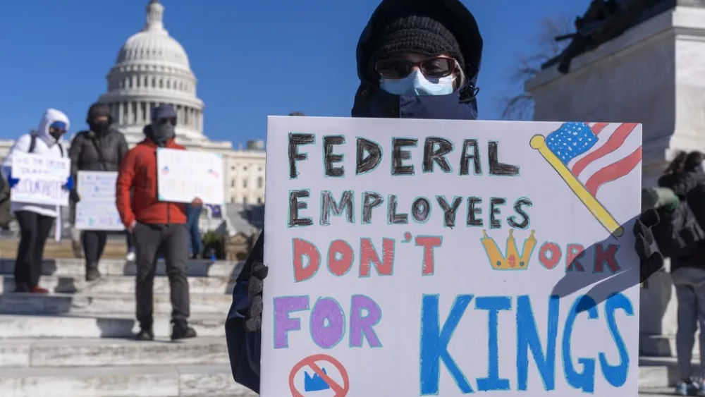 FILE - A federal employee, who asked not to use their name for fears over losing their job, protests with a sign saying "Federal Employees Don't Work for Kings" during the "No Kings Day" protest on Presidents Day , Feb. 17, 2025, near the Capitol in Washington. (AP Photo/Jacquelyn Martin, File)