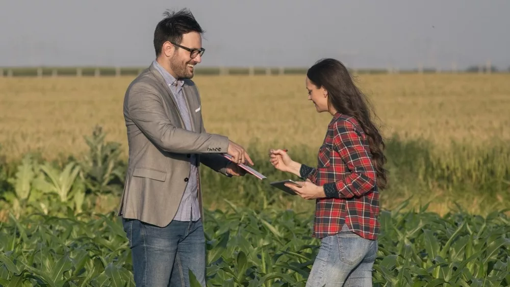 farmer-woman-signing-papers-with-businessman-in-field