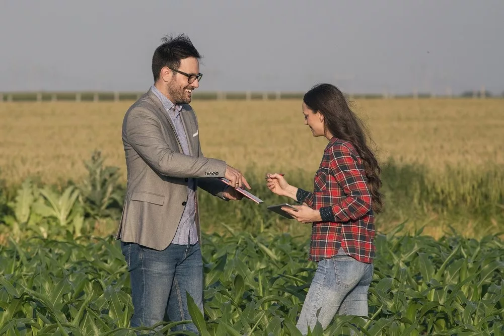 farmer-woman-signing-papers-with-businessman-in-field