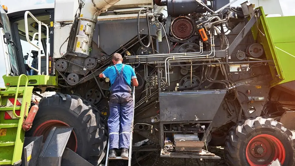 combine-machine-service-mechanic-repairing-motor-outdoors