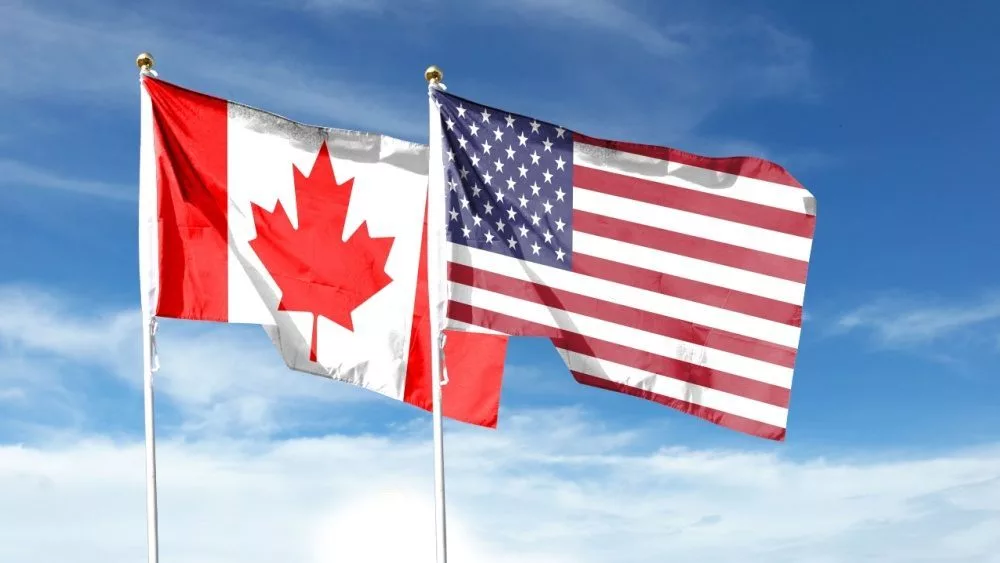 USA and Canada flags against cloudy sky. waving in the sky