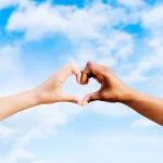 two-multiethnic-hands-join-together-to-form-a-shape-heart-with-a-blue-sky-clouds-background-concept-of-hope-and-love-between-different-races-peace-between-humans-and-against-hatred-and-racism