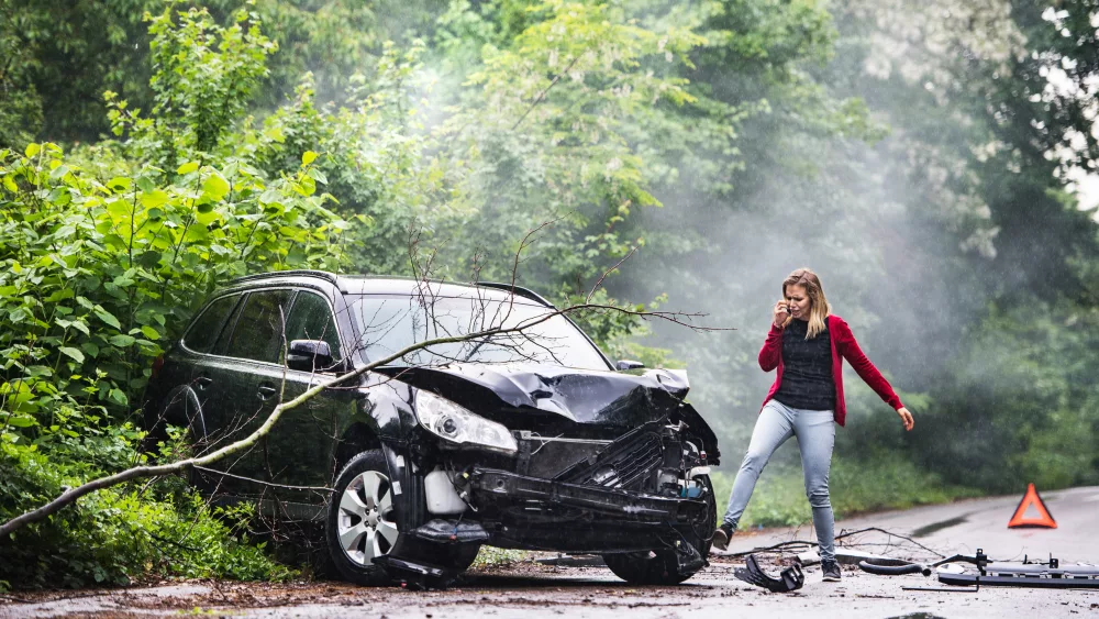 an-angry-young-woman-with-smartphone-by-the-damaged-car-after-a-car-accident