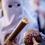 person-in-white-traditional-mask-holding-a-decorative-scepter-at-a-cultural-event