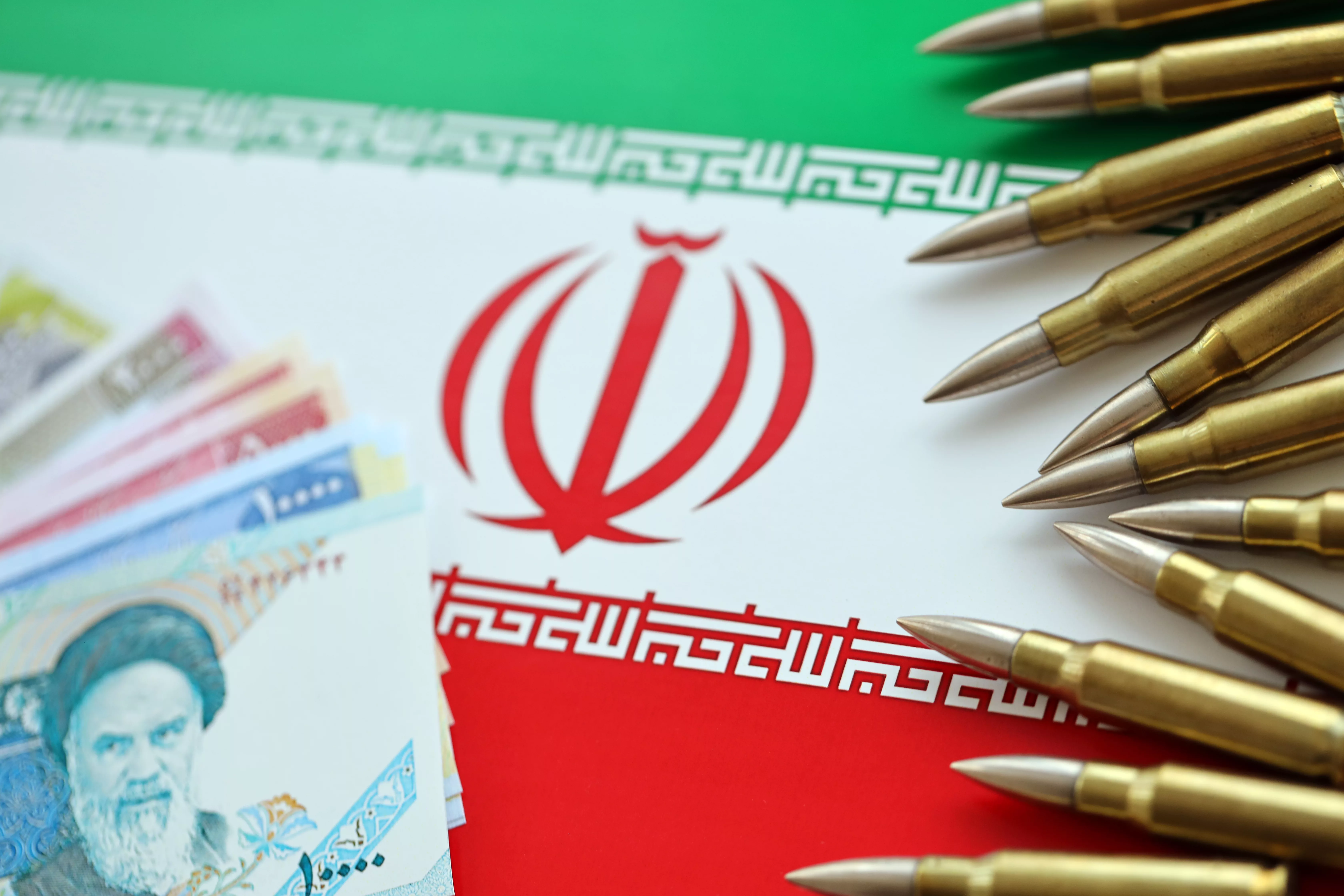 many-bullets-and-iranian-rials-money-bills-on-flag-of-islamic-republic-of-iran
