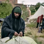 young-male-migrant-pitching-tent-in-refugee-camping