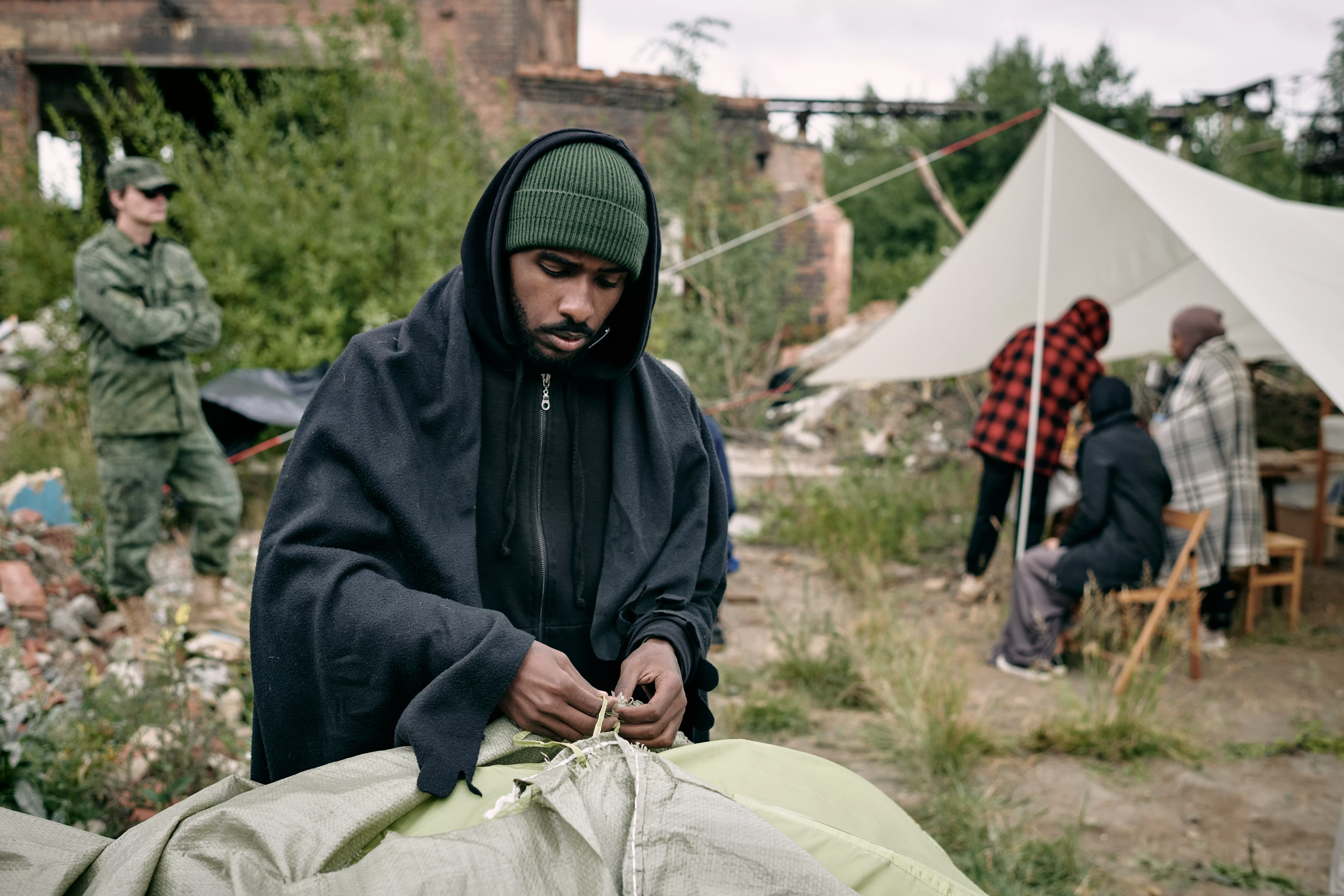 young-male-migrant-pitching-tent-in-refugee-camping