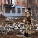 a-ukrainian-serviceman-stands-next-to-the-shelling-of-a-civilian-building-in-kherson-by-the-russian