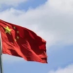 chinese-flag-attached-to-a-pole-under-a-blue-sky-in-the-wind