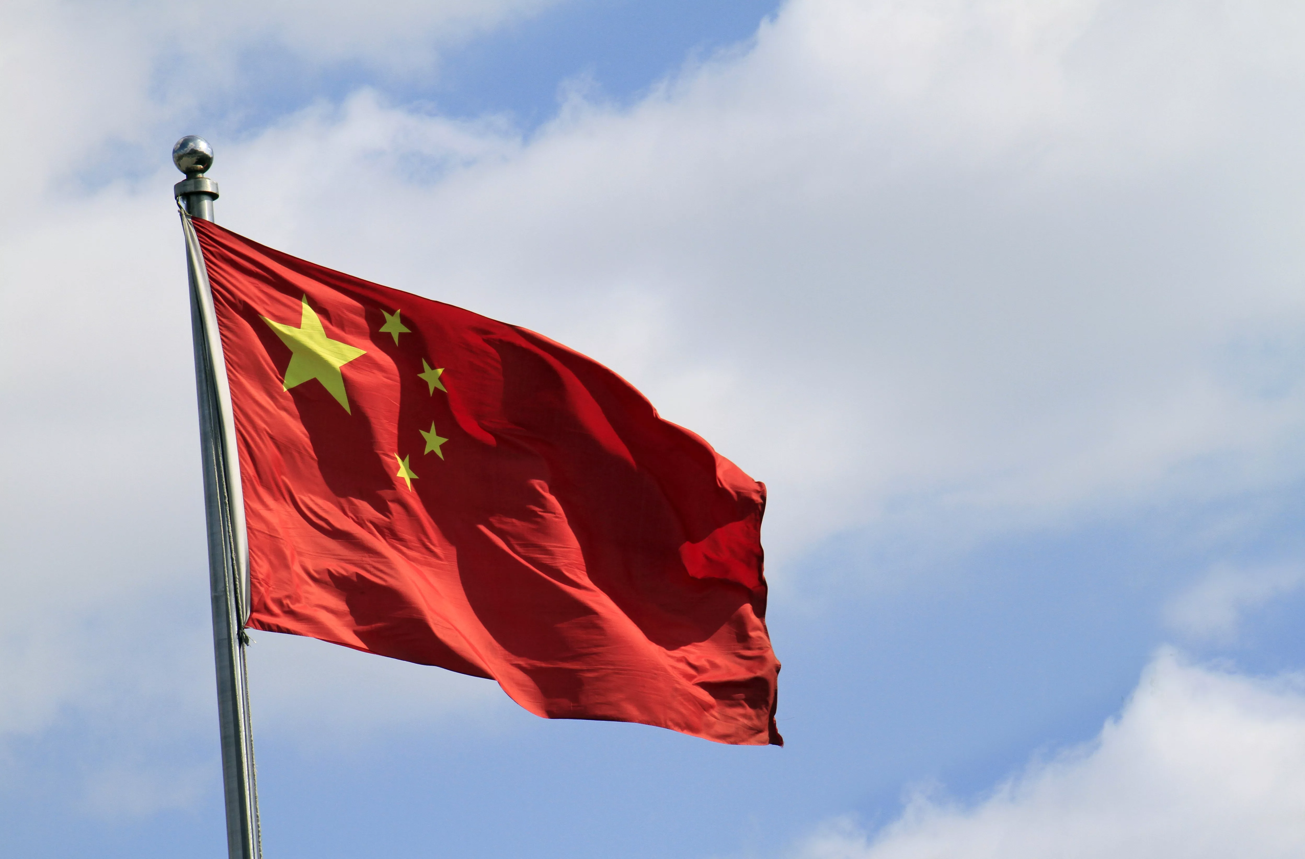 chinese-flag-attached-to-a-pole-under-a-blue-sky-in-the-wind