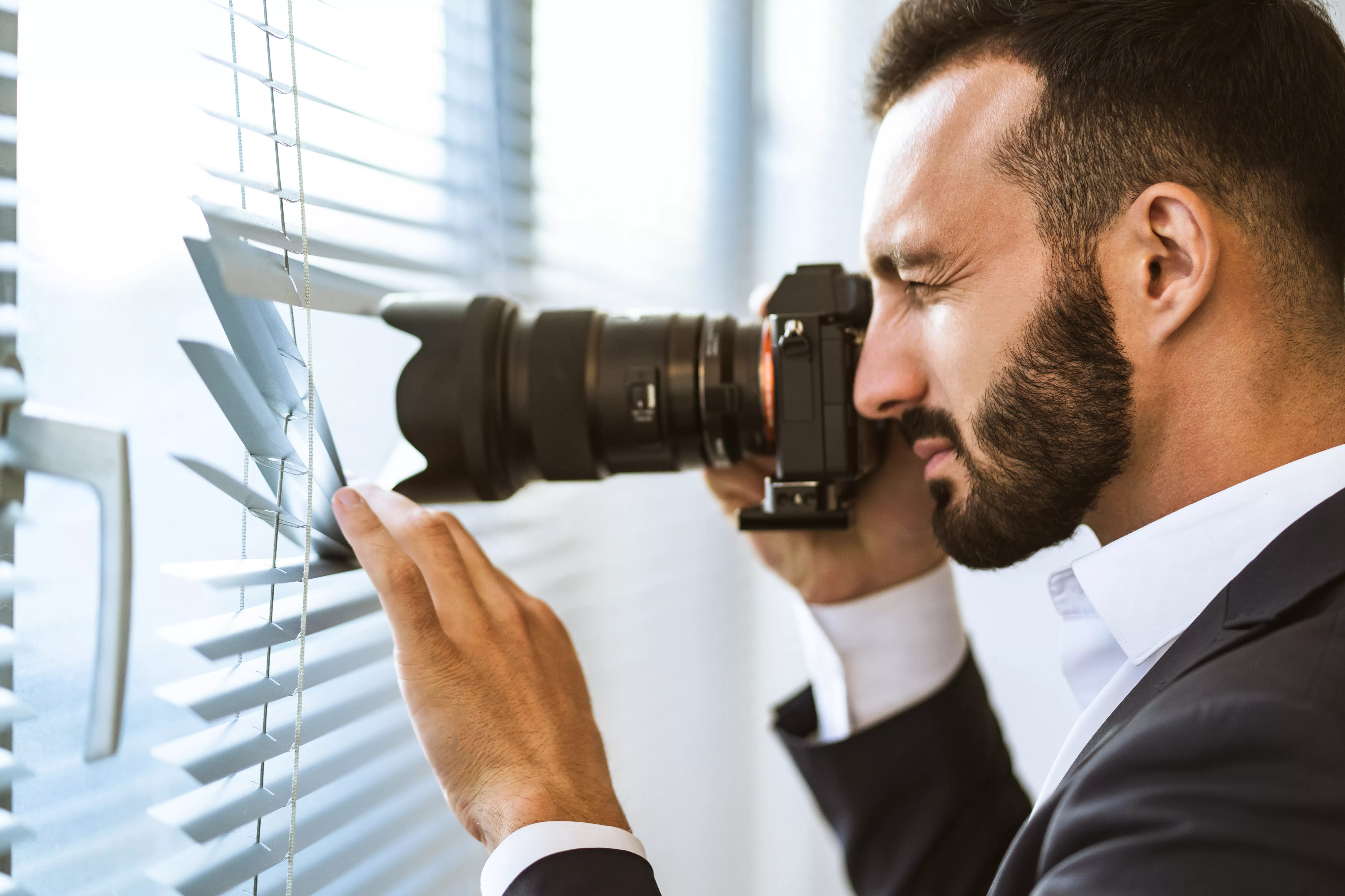 the-man-with-a-camera-photographing-through-the-blinds