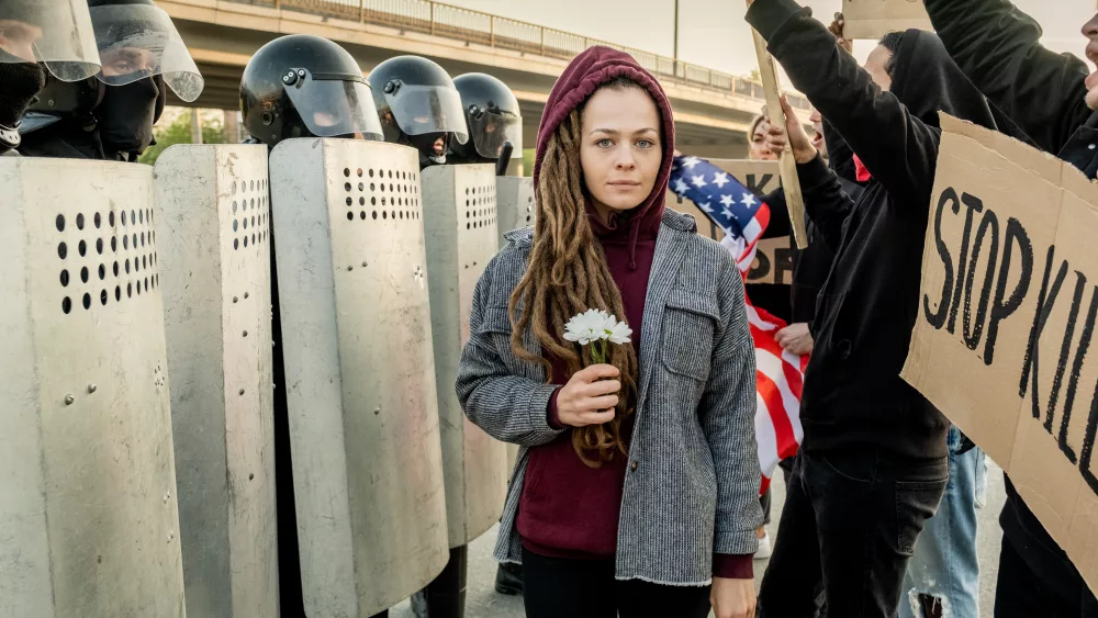 woman-between-displeased-crowd-and-riot-police