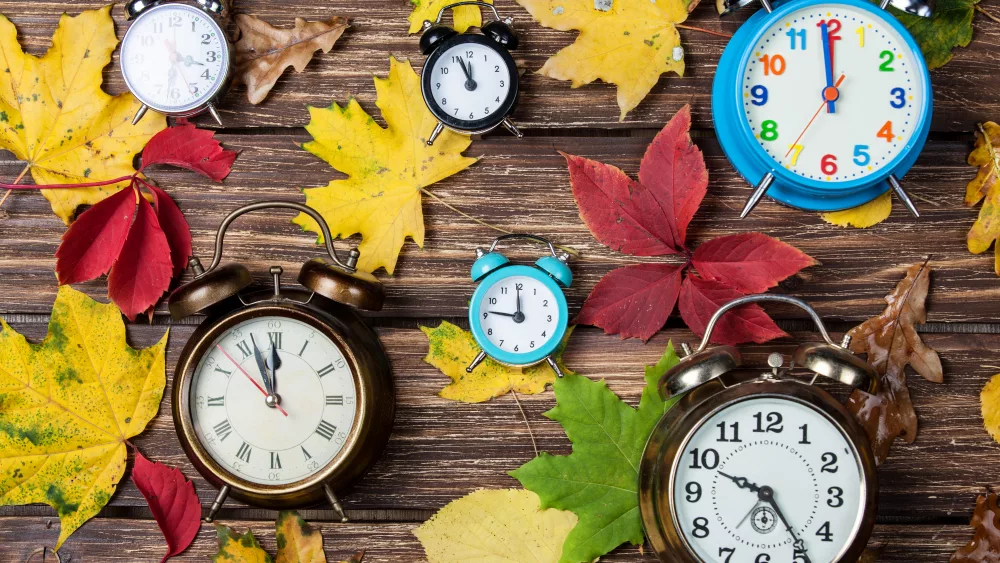 autumn-leafs-and-alarm-clock-on-wooden-table