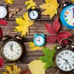 autumn-leafs-and-alarm-clock-on-wooden-table