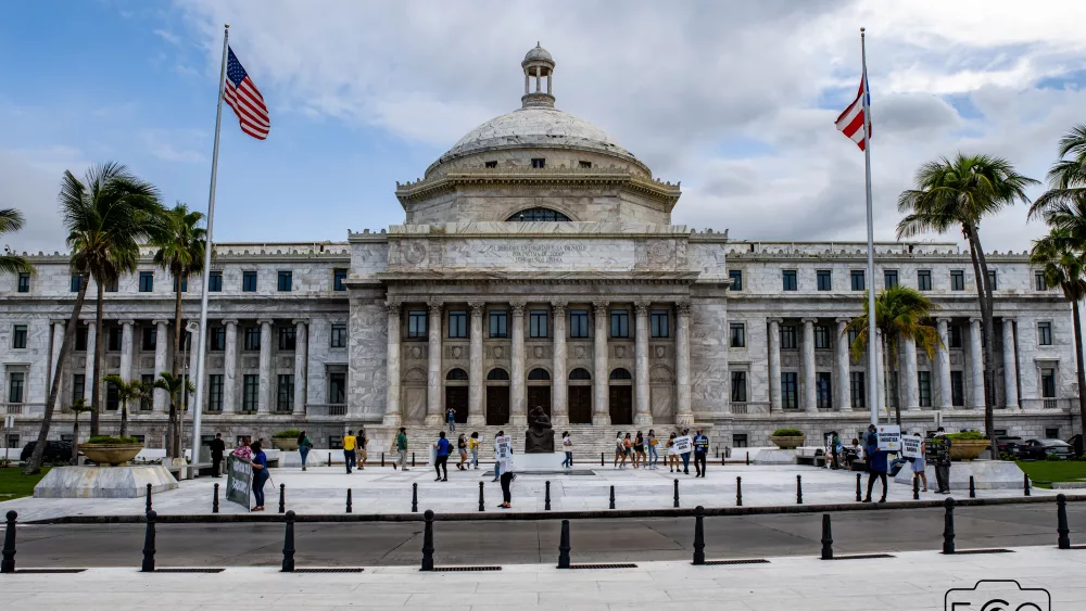 the-front-entrance-of-a-building-with-some-columns-and-two-flags-on-poles