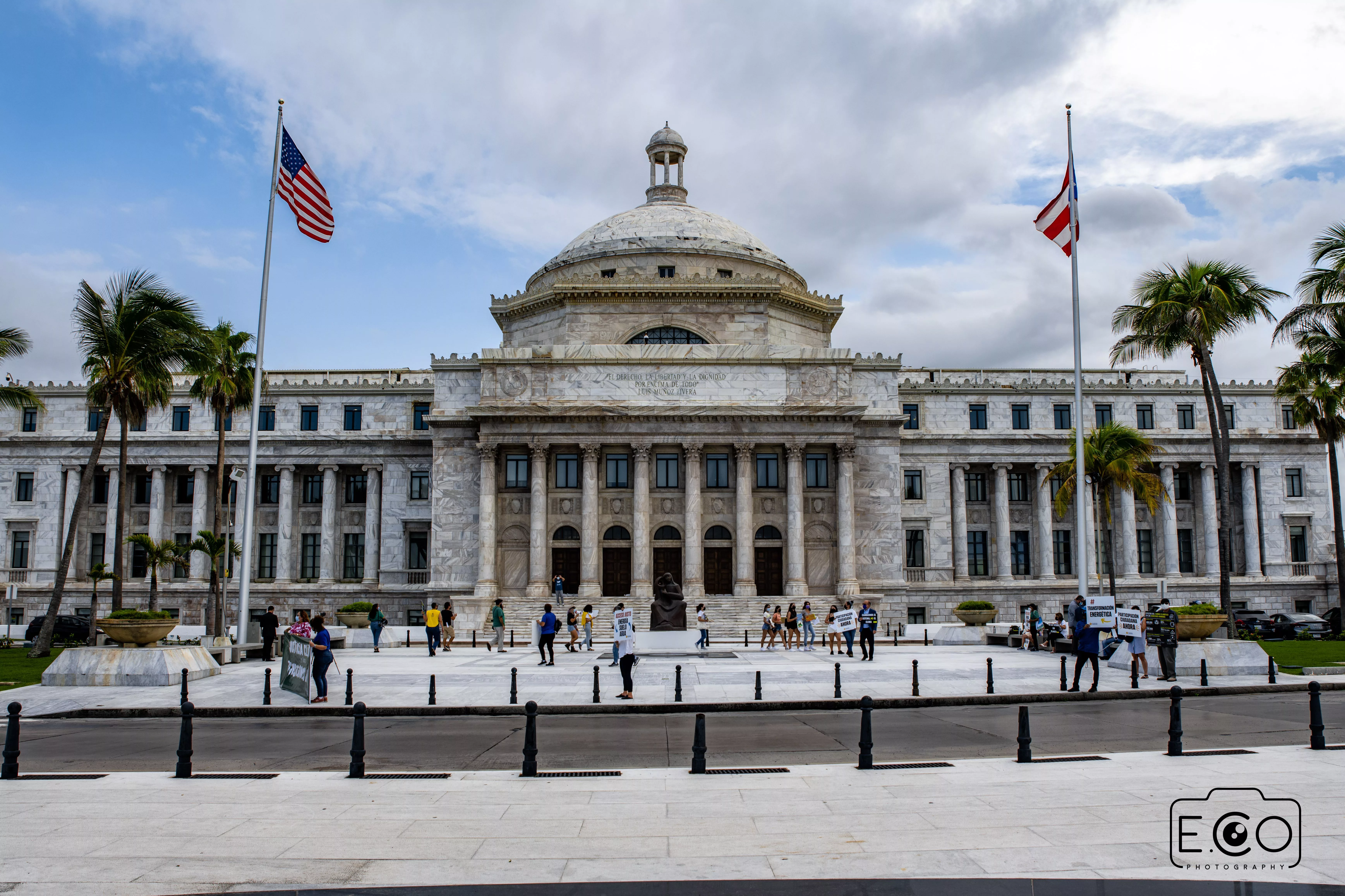 the-front-entrance-of-a-building-with-some-columns-and-two-flags-on-poles