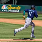 Seattle Mariners infielder Carlos Santana runs to first base against the Oakland Athletics at the Oakland Coliseum. Oakland^ California - August 21^ 2022