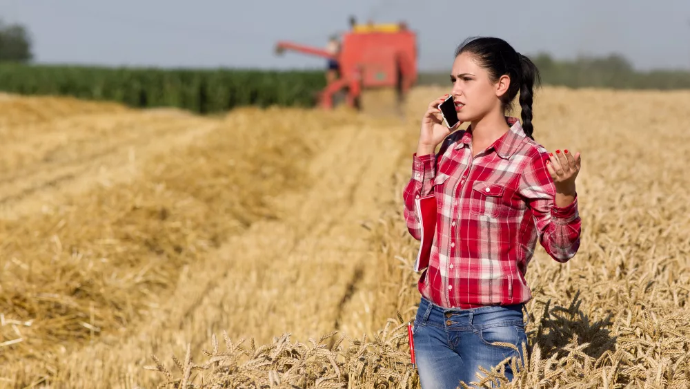 Woman standing in field talking on cell phone.