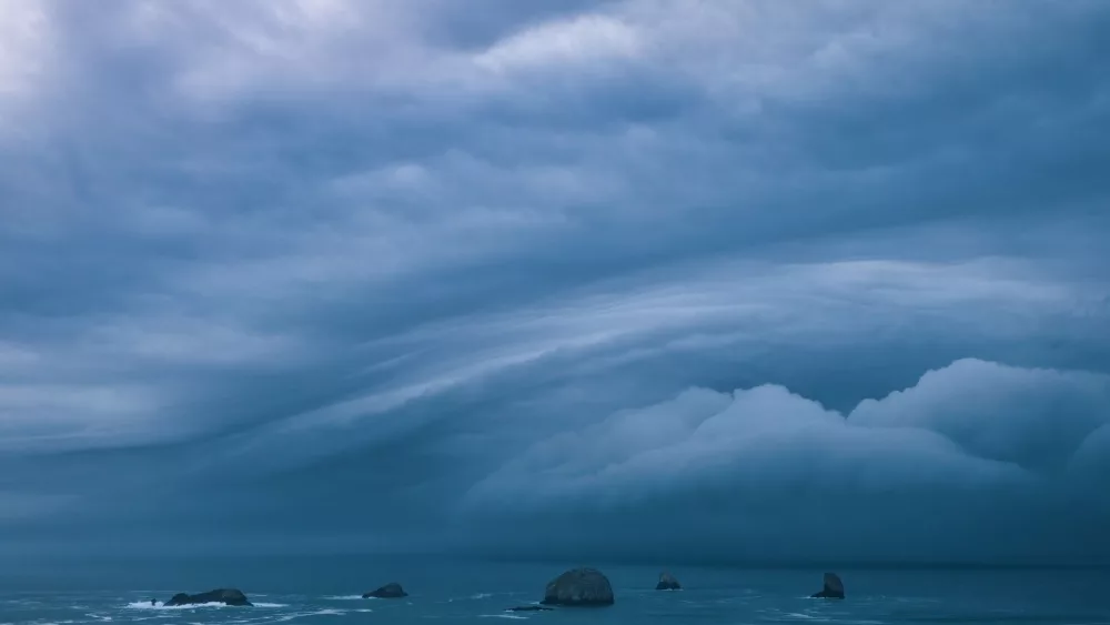 Storm clouds from bomb cyclone over sea stacks in the ocean at the Oregon Coast.