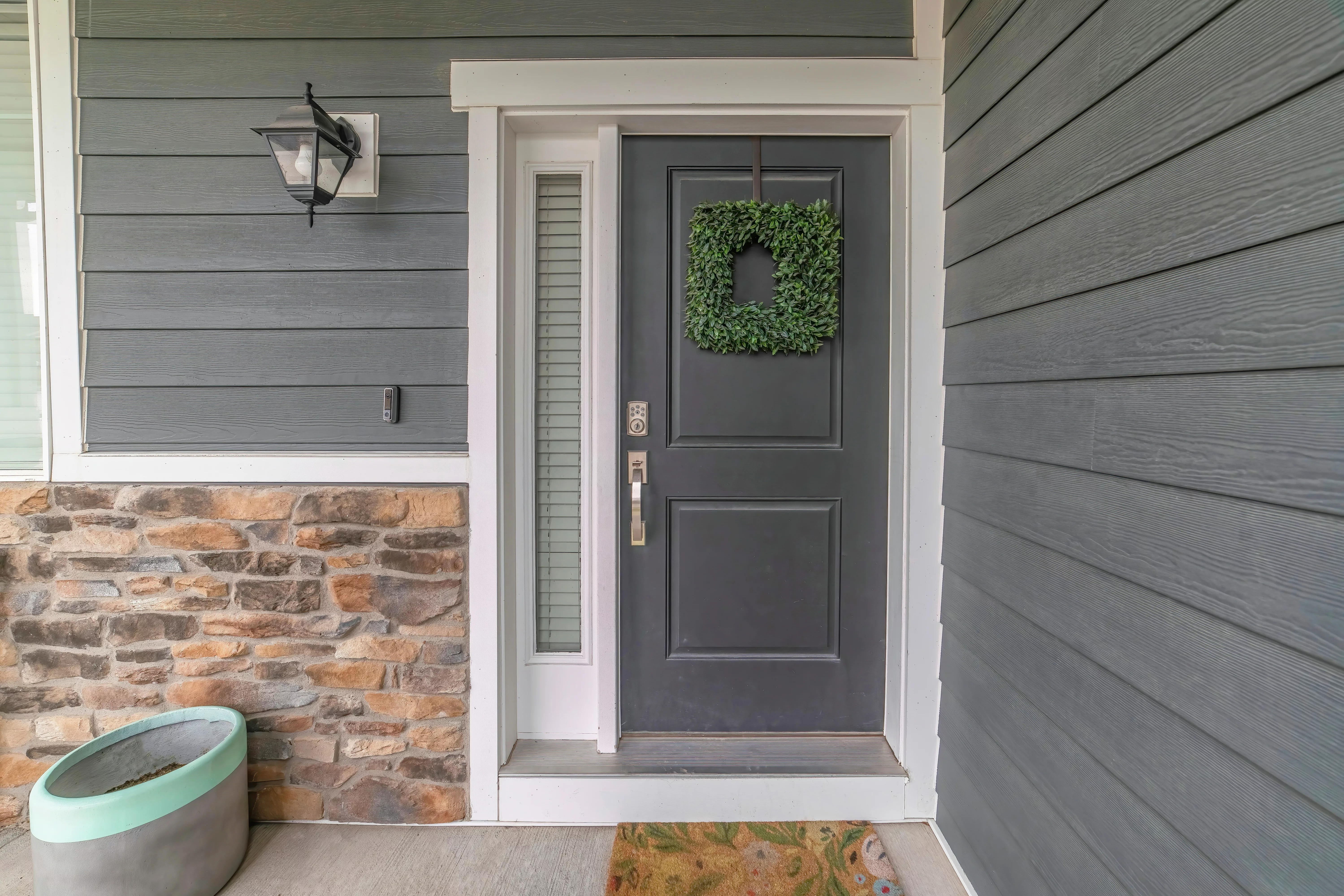 entrance-to-a-house-with-side-light-and-gray-front-door-decorated-with-wreath