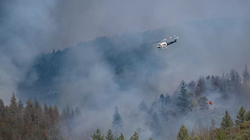 A helicopter dropping water on the Salt Creek Fire