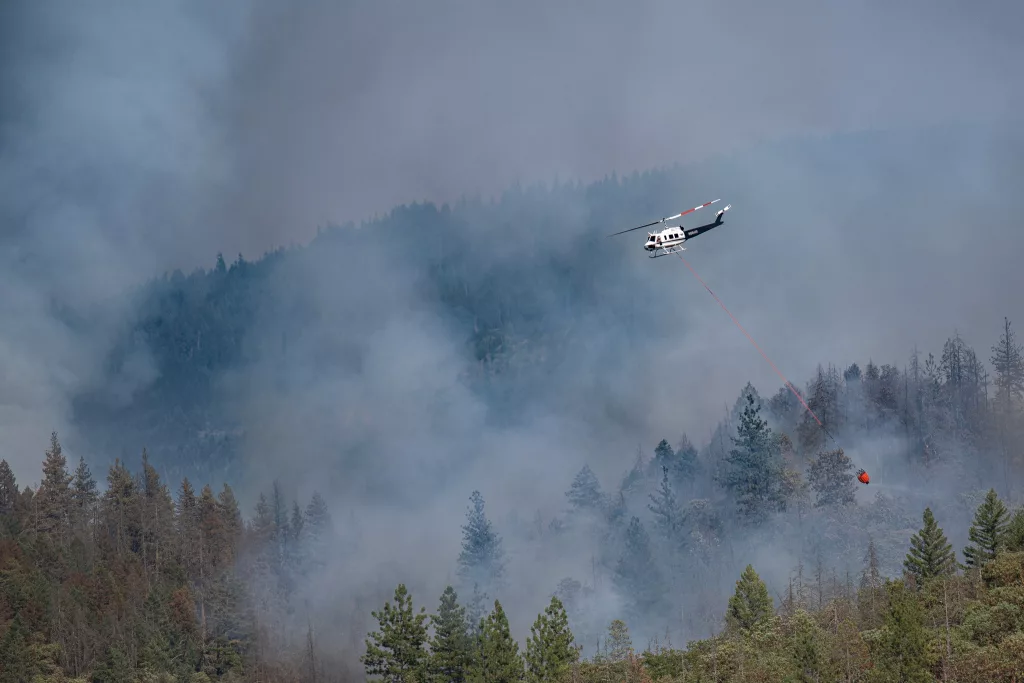 A helicopter dropping water on the Salt Creek Fire