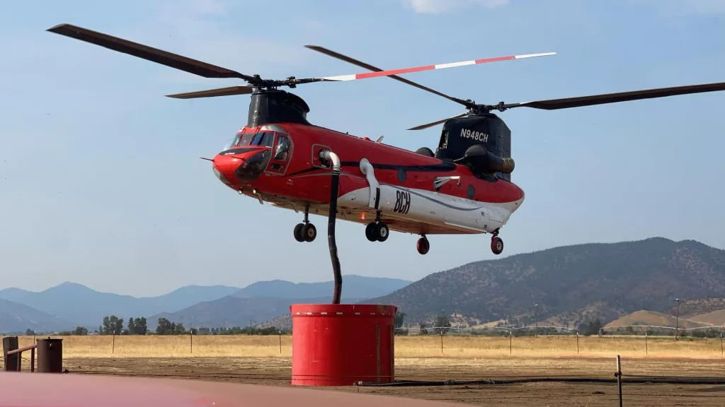 A helicopter picking up water to drop on the Shelly Fire