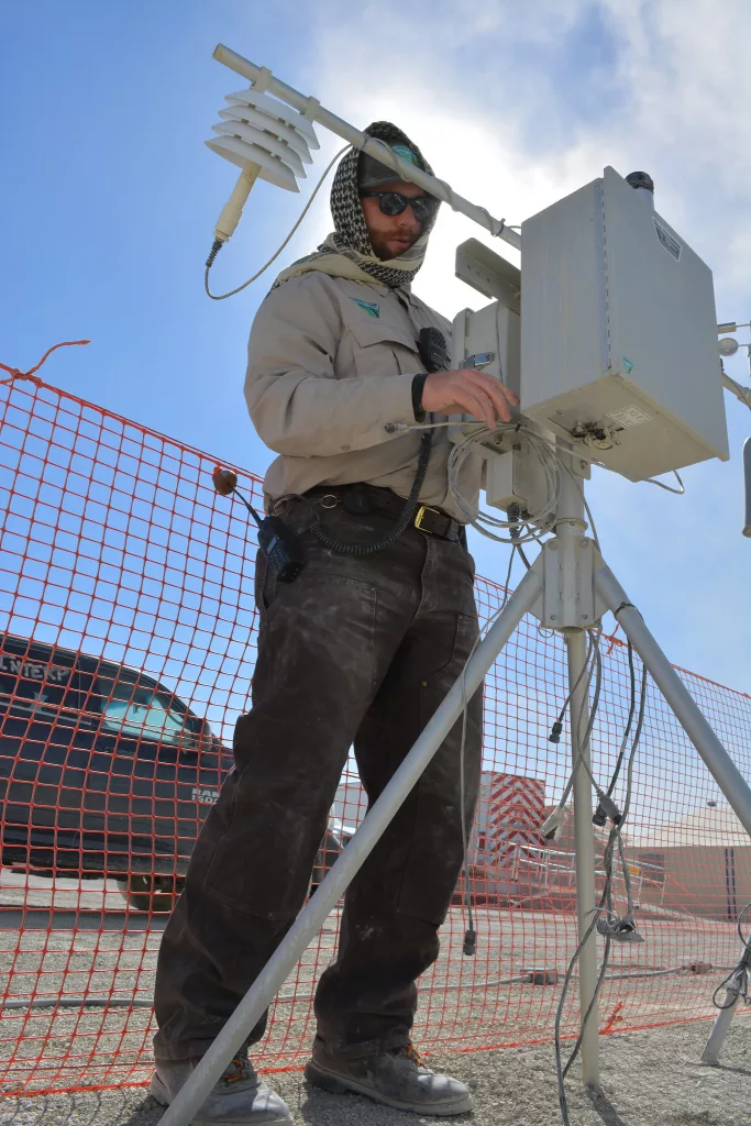 Denis Baldwin, BLM Safety Officer for Burning Man 2019, helps set up a particulate matter monitor near the BLM Interpretive Camp and Law Enforcement Substation in Black Rock City. The monitor measures airborne particulate matter