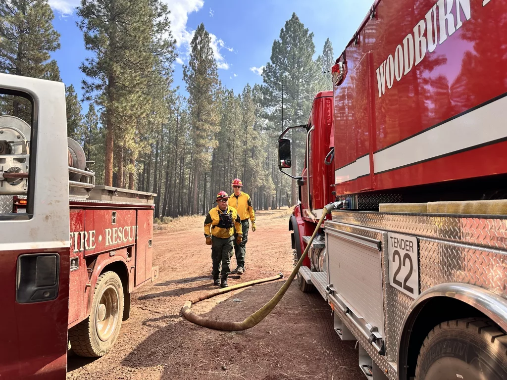 Firefighters stand near trucks on the Copperfield Fire