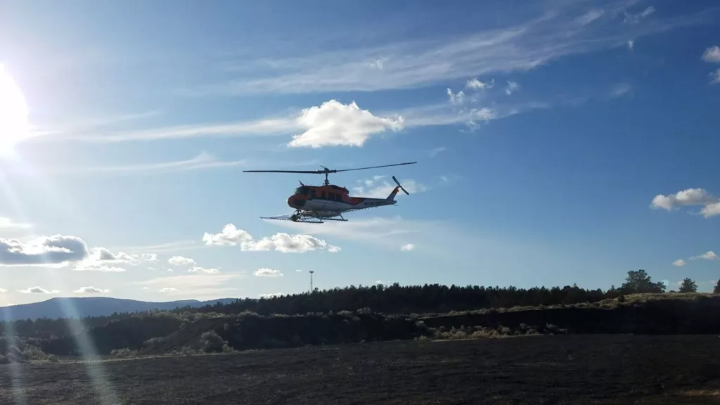 A helicopter conducting aerial spraying