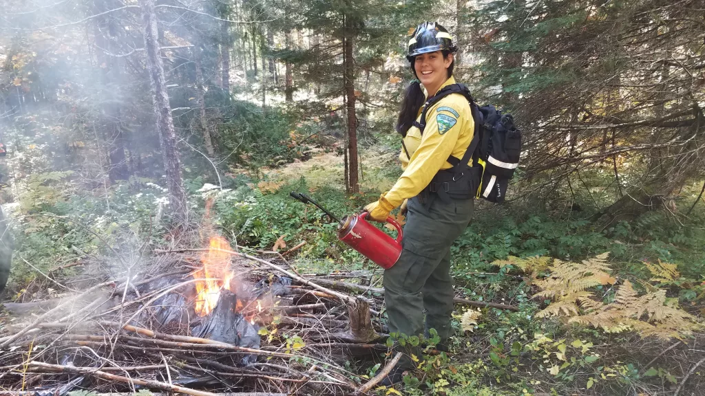 A firefighter burning a pile of debris during a prescribed burn