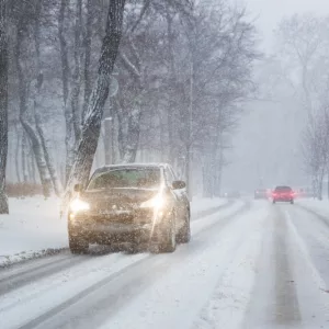 carsmovingonslipperysnowyroadatcitystreetduring