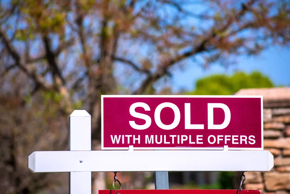 soldwithmultipleoffersrealestatesignnearpurchasedhouse