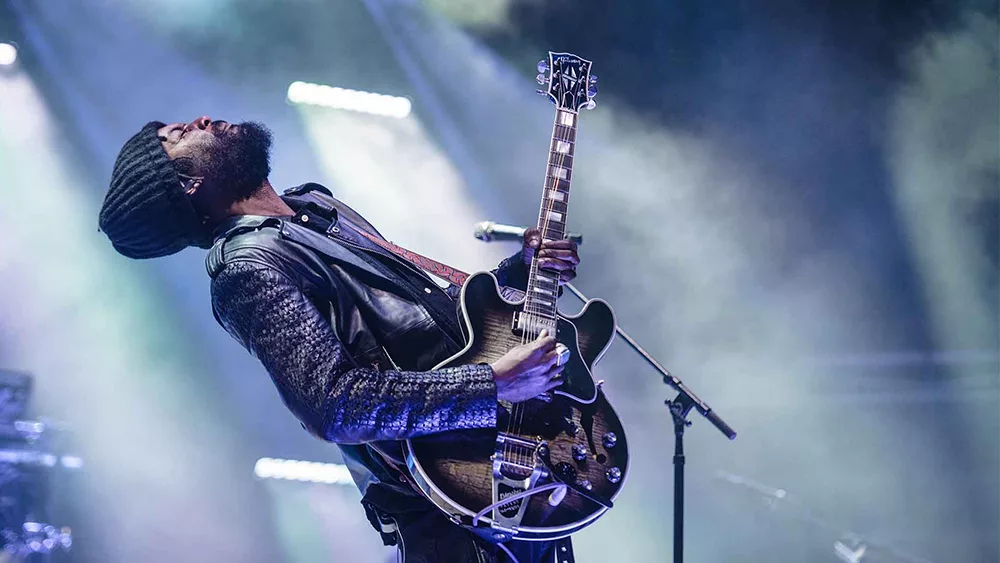 Gary Clark Jr on stage with a guitar.