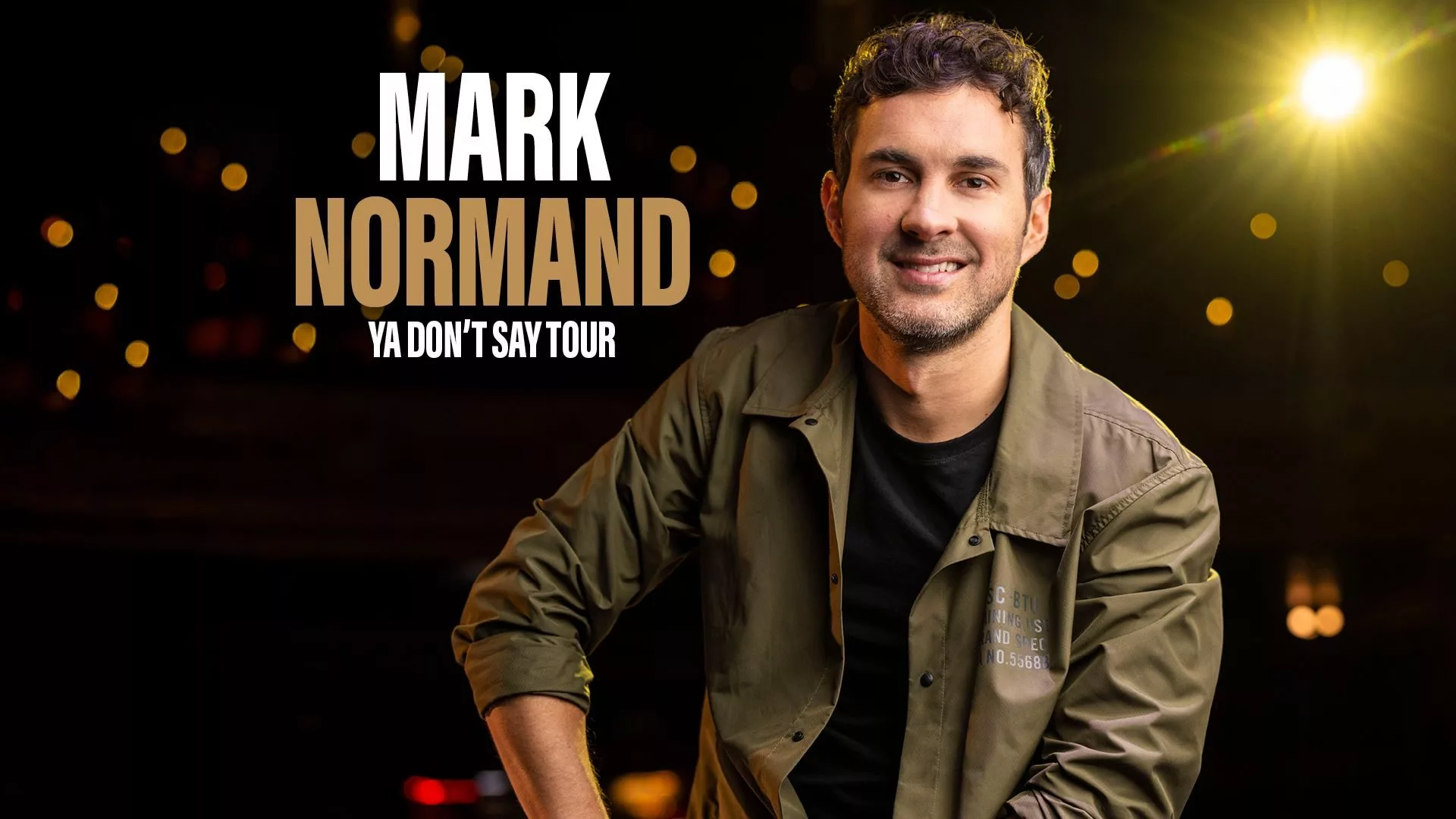 Mark Normand Ya Don't Say Tour, show graphics. Mark in a button up on a stool on stage.