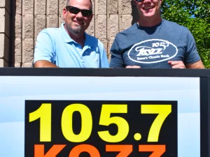 Kevin & Jay standing by sign with KOZZ logo