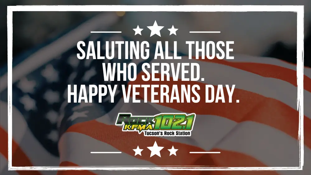 “Close-up of an American flag with white border and stars above and below the text. Bold white message reads ‘Saluting all those who served. Happy Veterans Day.’ Rock 102.1 KFMA Tucson’s Rock Station logo centered underneath.”