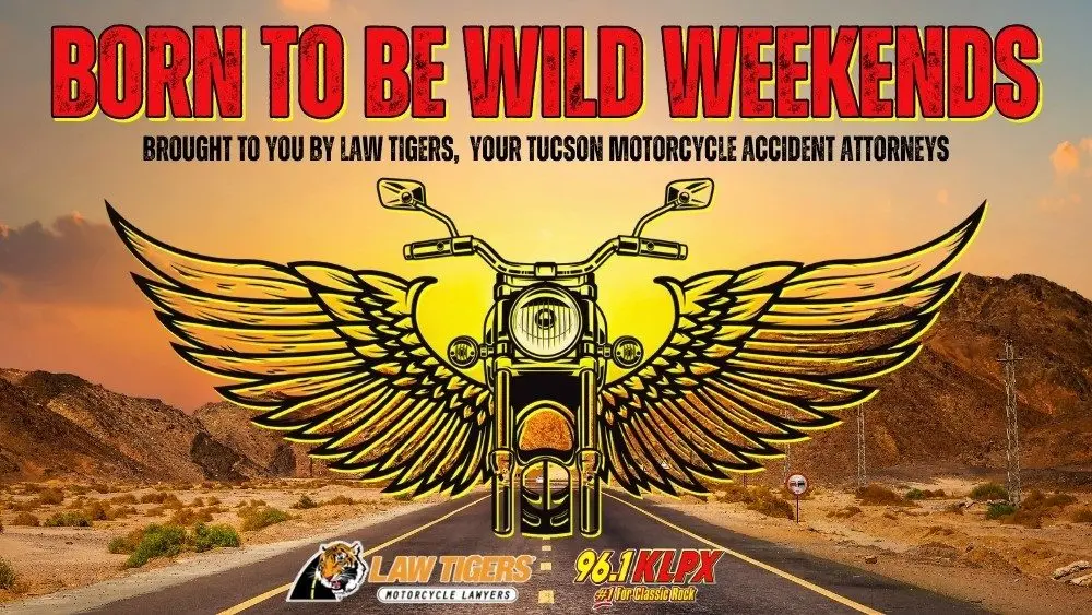 Promotional image for "Born to Be Wild Weekends," featuring a stylized motorcycle with large golden wings on an open desert road at sunset. Bold red and yellow text at the top reads, "Born to Be Wild Weekends." Below, it says, "Brought to you by Law Tigers, your Tucson motorcycle accident attorneys." At the bottom are logos for Law Tigers Motorcycle Lawyers and 96.1 KLPX, labeled as "#1 for Classic Rock.