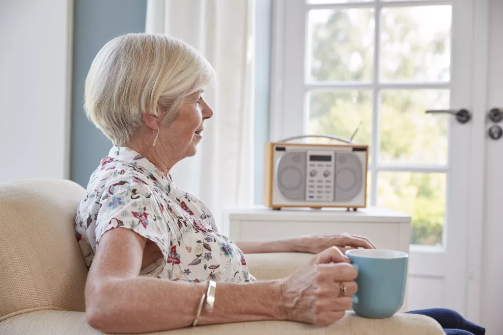 senior-woman-drinking-tea-and-listening-to-radio-at-home