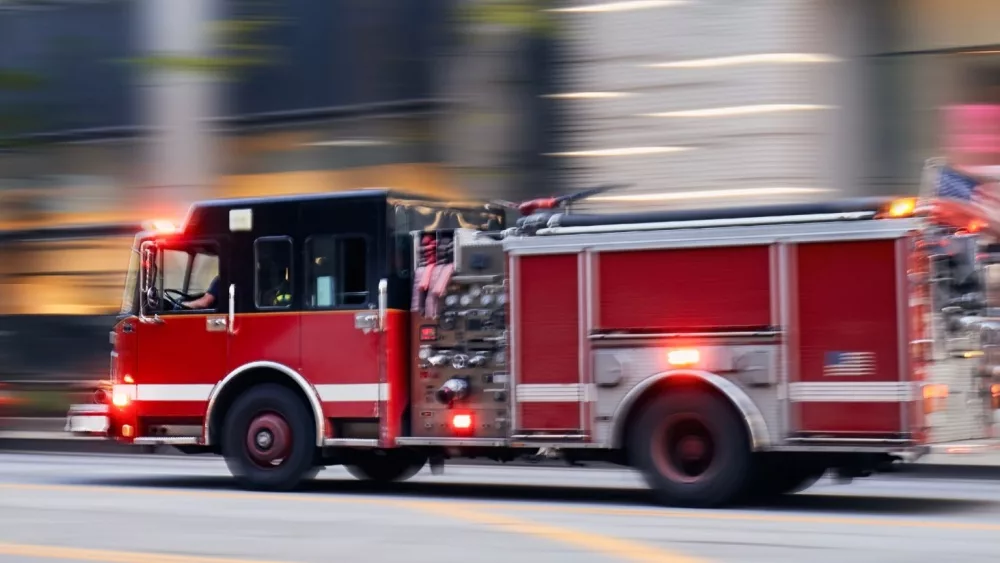 Fast moving fire engine on city street. Firefighters in blurred motion.