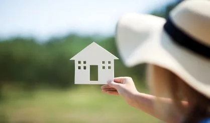 woman-holding-house-model-in-the-countryside