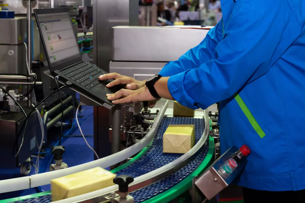 manufacturing-engineer-used-computer-to-control-product-inspection-system-automation-machine-in-modern-factory-while-products-are-moving-on-the-conveyor-belt-to-warehouse-for-logistic-transport