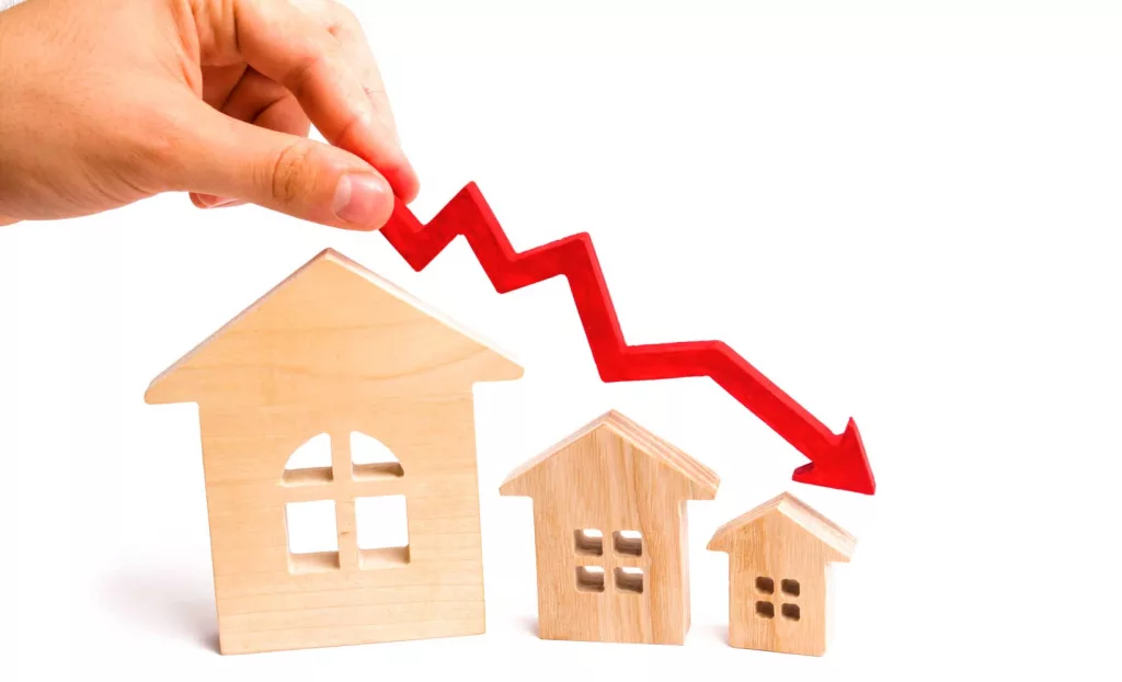 the-hand-holds-a-red-arrow-above-the-wooden-houses-down-the-houses-are-decreasing-the-concept-of-falling-demand-and-supply-in-the-real-estate-market-economic-crisis-the-fall-in-prices-5