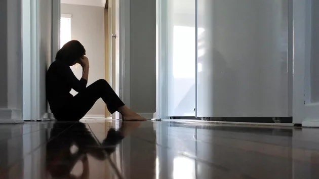 sad-woman-sitting-on-dark-home-corridor-floor