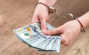 female-holds-money-dollars-in-handcuffed