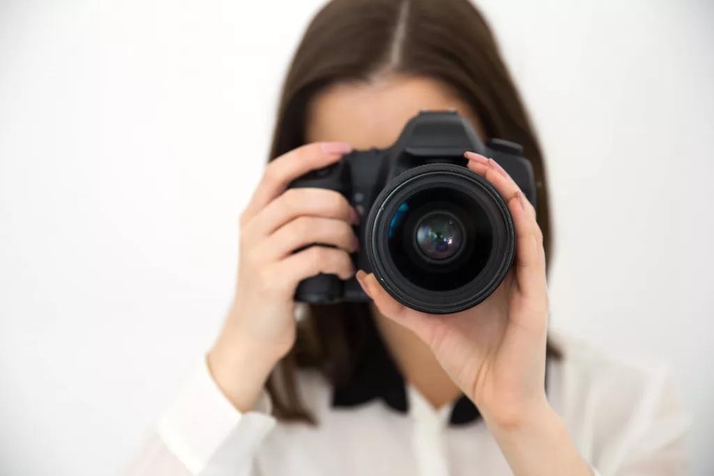 woman-photographer-with-camera-over-gray-background