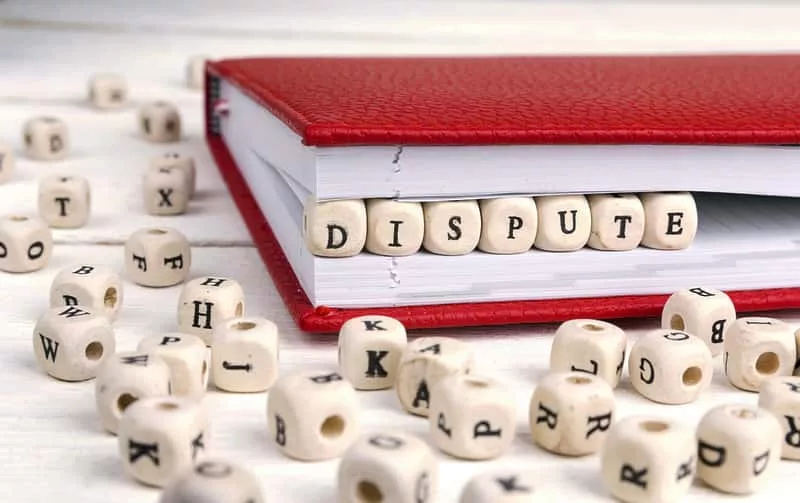 word-dispute-written-in-wooden-blocks-in-red-notebook-on-white-w