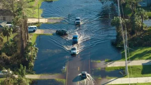 Flooded road in Florida after heavy hurricane rainfall. Aerial view of evacuating cars and surrounded with water houses in suburban residential area