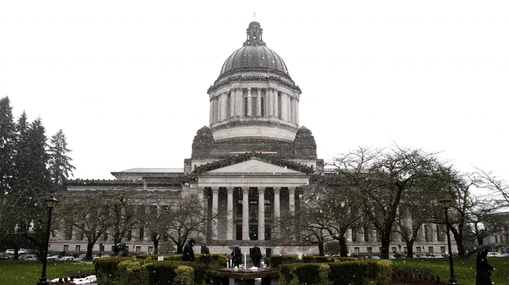 Snow falls as pedestrians walk near the Legislative Building, Wednesday, Feb. 8, 2017, at the Capitol in Olympia, Wash. (AP Photo/Ted S. Warren)